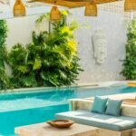 Home Elegant outdoor pool area featuring tropical plants and modern seating for relaxation.